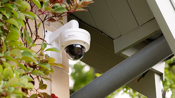 A camera hanging on the wall outside a house